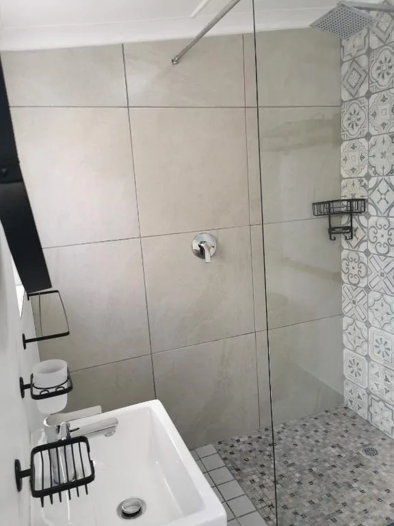 Modern bathroom with walk-in shower, white tiles, and vanity sink