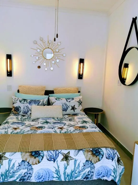 Coastal-themed bedroom with seafaring bedding and decorative sunburst mirror above bed