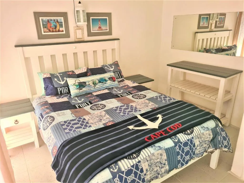 Nautical-themed bedroom with white headboard and coastal bedding