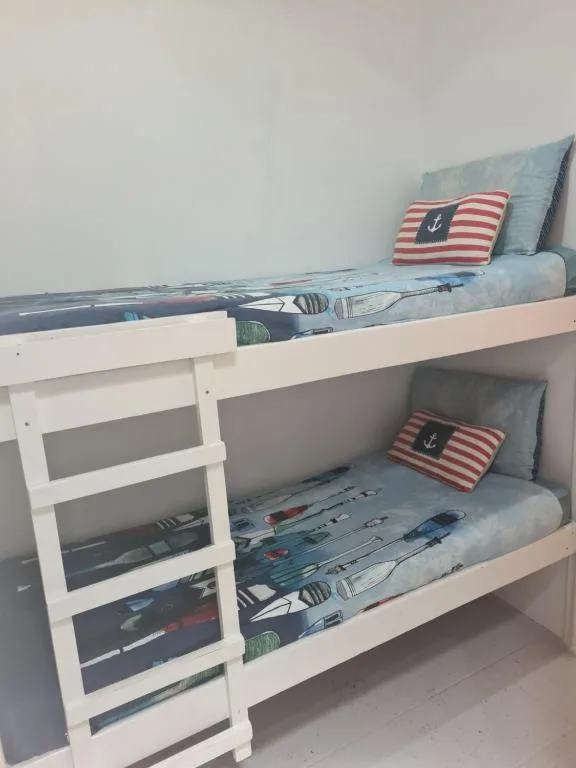 White bunk bed with nautical themed bedding and striped pillows