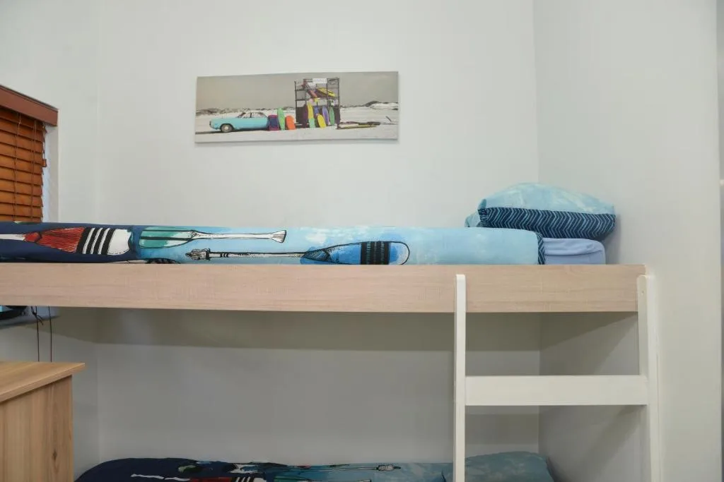 Bunk bed with neatly folded linens and beach-themed wall decoration