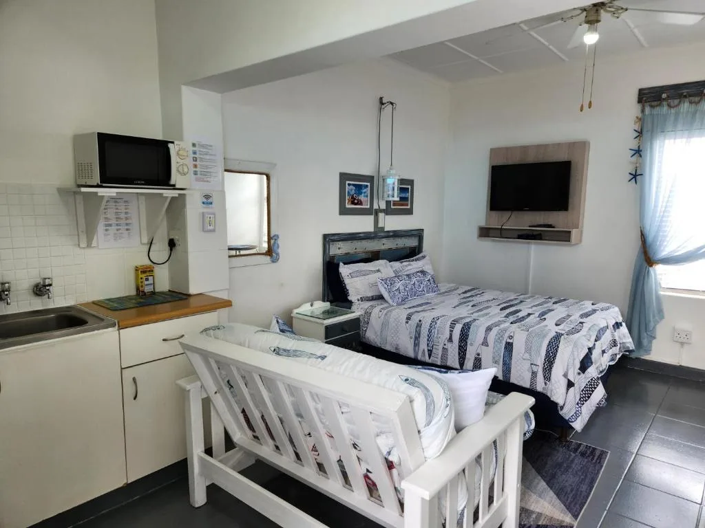 Studio bedroom with double bed, kitchenette, crib, and wall-mounted TV