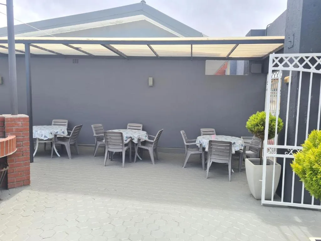 Covered patio area with dining tables and chairs under pergola shade