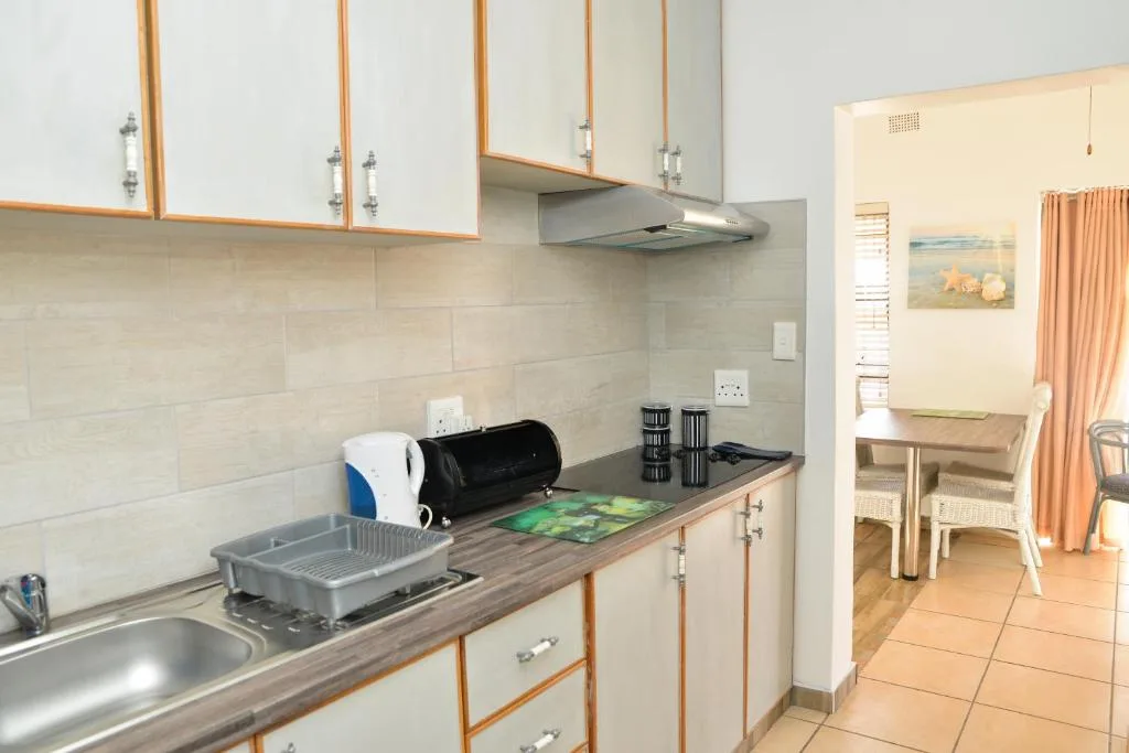 Compact kitchen with wooden cabinetry, stainless steel sink, and gas cooktop