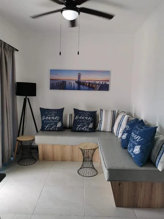 Modern living room with gray sofa, coastal artwork, and ceiling fan