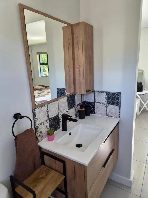 Modern bathroom vanity with white sink, wooden cabinetry, and framed mirror