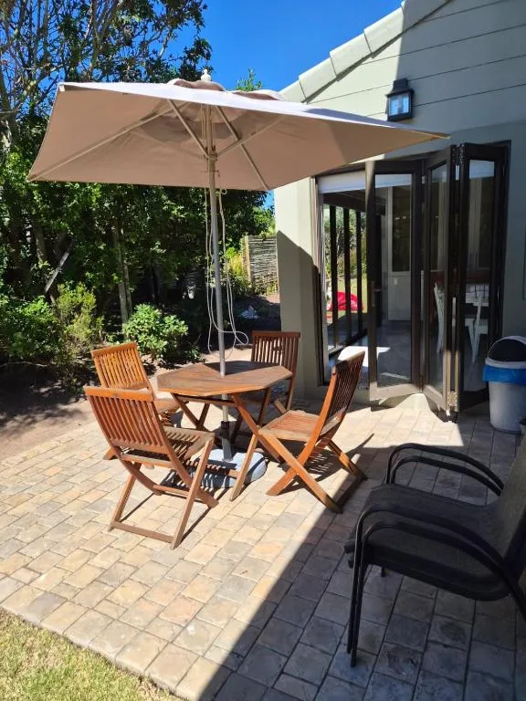 Outdoor patio with wooden dining furniture and beige umbrella shade