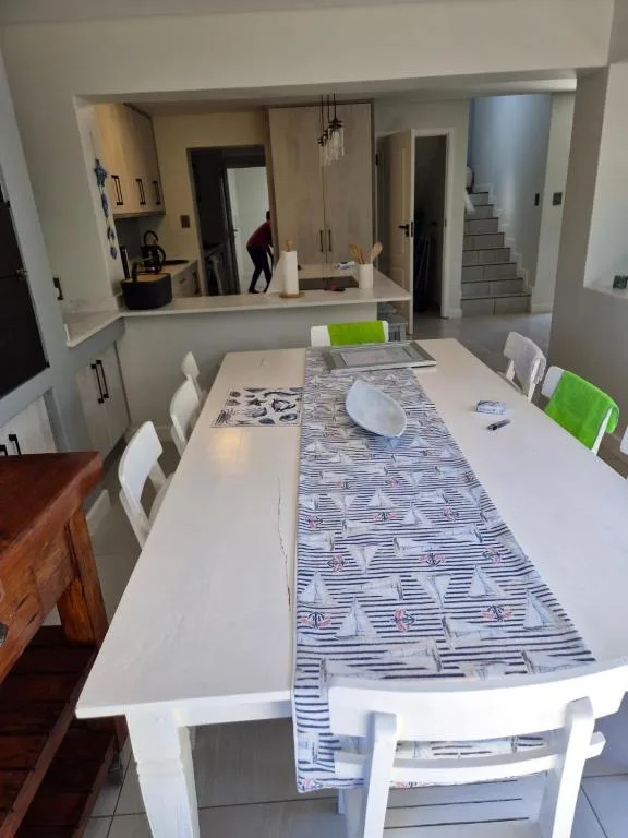 Modern dining table with white chairs and blue striped table runner