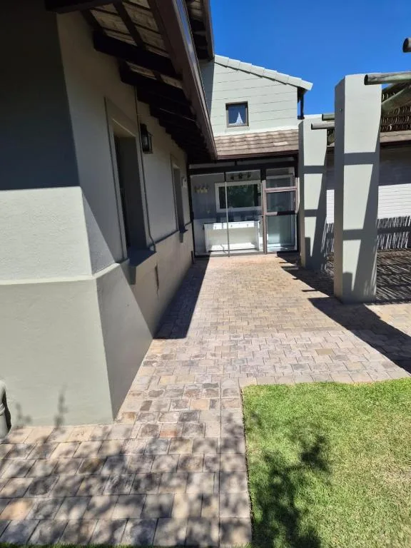 Modern white villa entrance with paved courtyard and manicured lawn