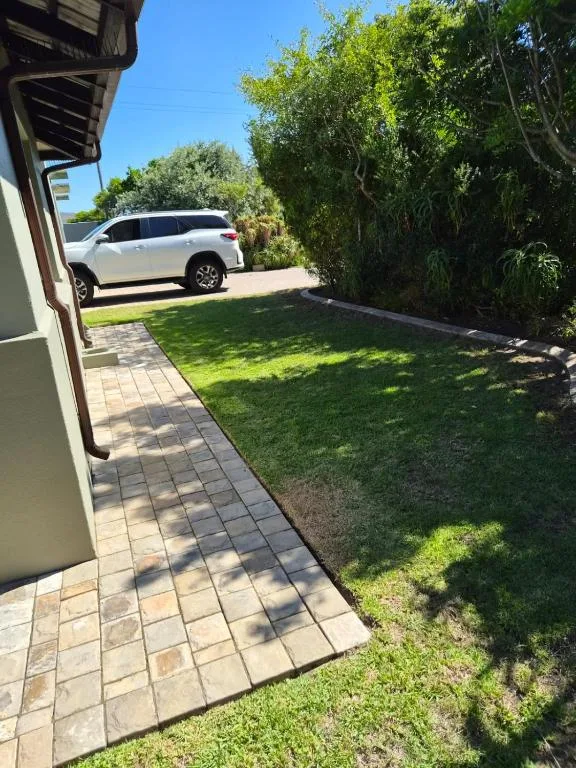 Paved pathway beside lush green lawn with parked white vehicle