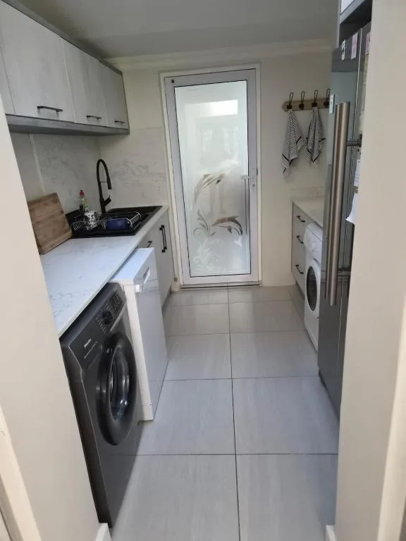 Modern kitchen with white cabinetry, black appliances, and washing machine