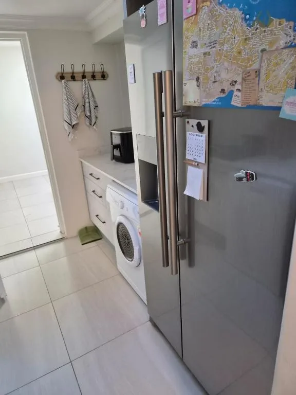 Modern kitchen with stainless steel fridge, washing machine, and storage