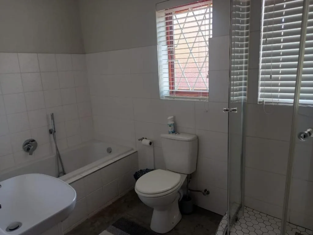 Clean white bathroom with toilet, bath tub, and shower enclosure