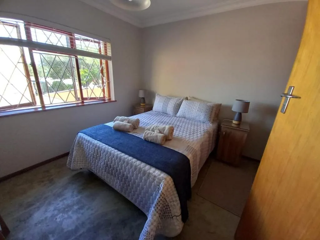 Spacious bedroom with double bed, patterned blue bedding, wooden nightstands with lamps