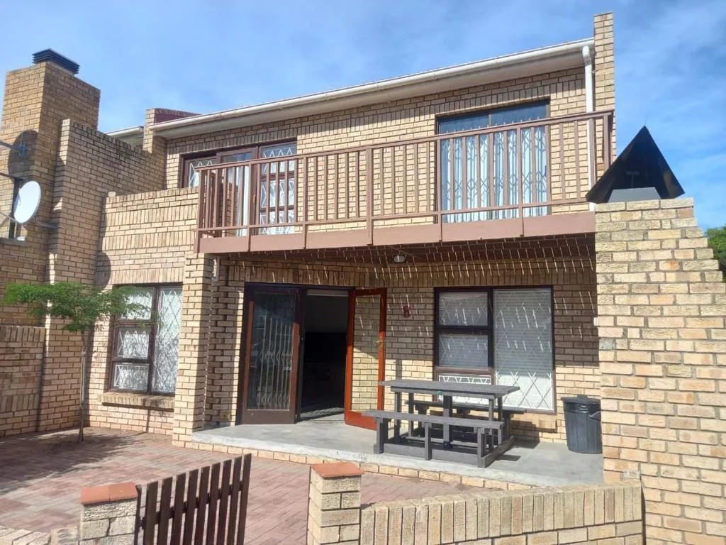 Brick holiday home with upper deck, large windows, and patio seating area