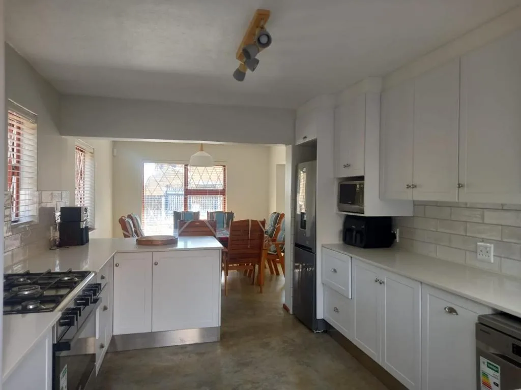 Modern kitchen with white cabinetry, gas stove, and open dining area beyond