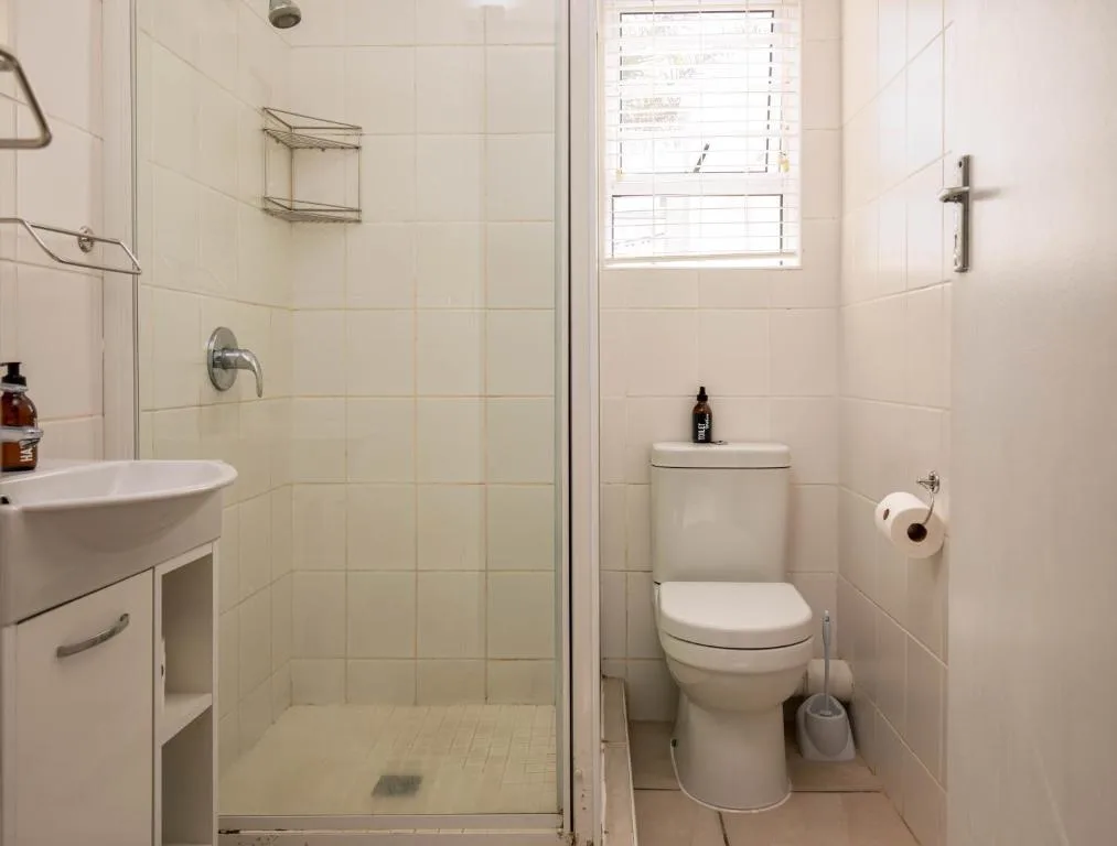 Clean bathroom with shower, sink, toilet, and window light
