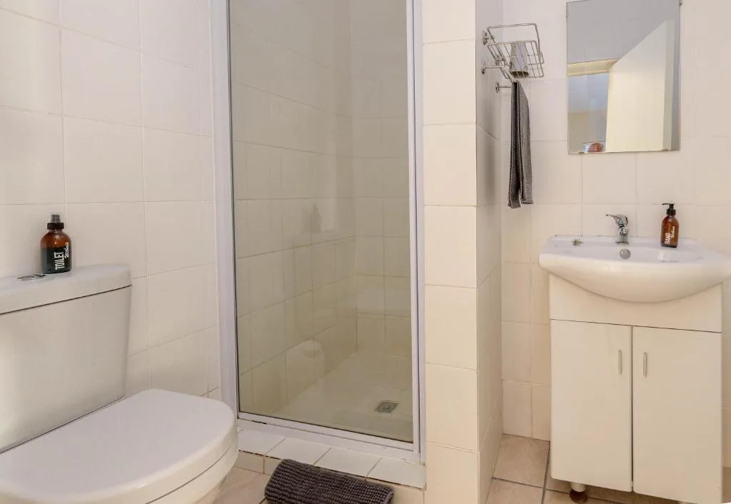 Clean white bathroom with shower enclosure, toilet, and pedestal sink