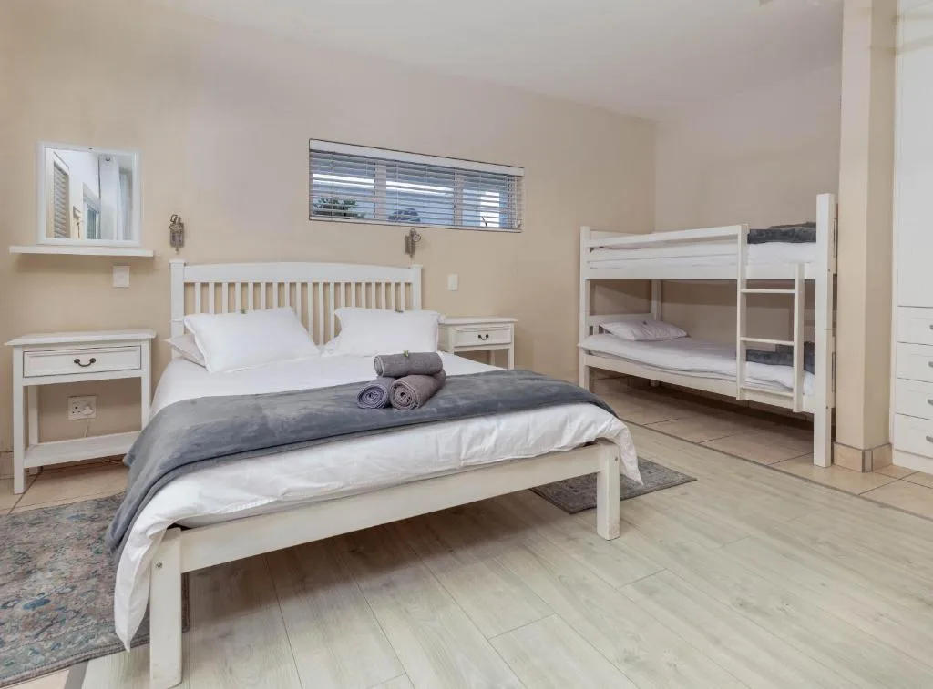 Spacious bedroom with double bed, bunk beds, white furniture, and wooden floors