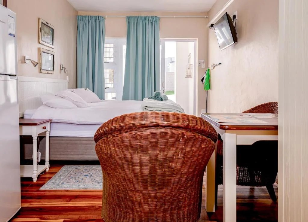 Bright bedroom with queen bed, turquoise curtains, and garden access
