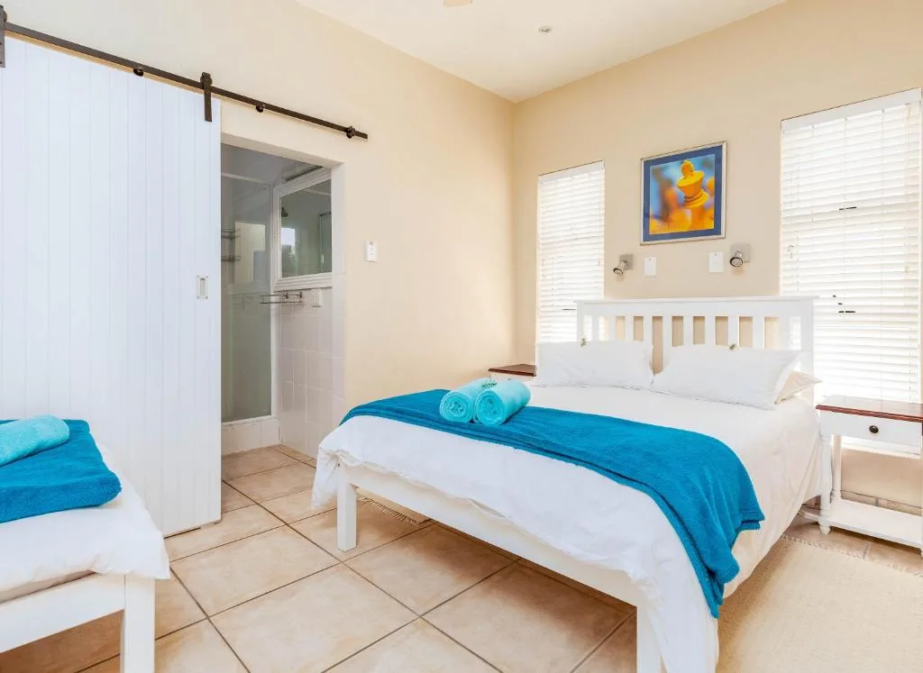 Bright bedroom with white bed, blue bedding, ensuite bathroom visible