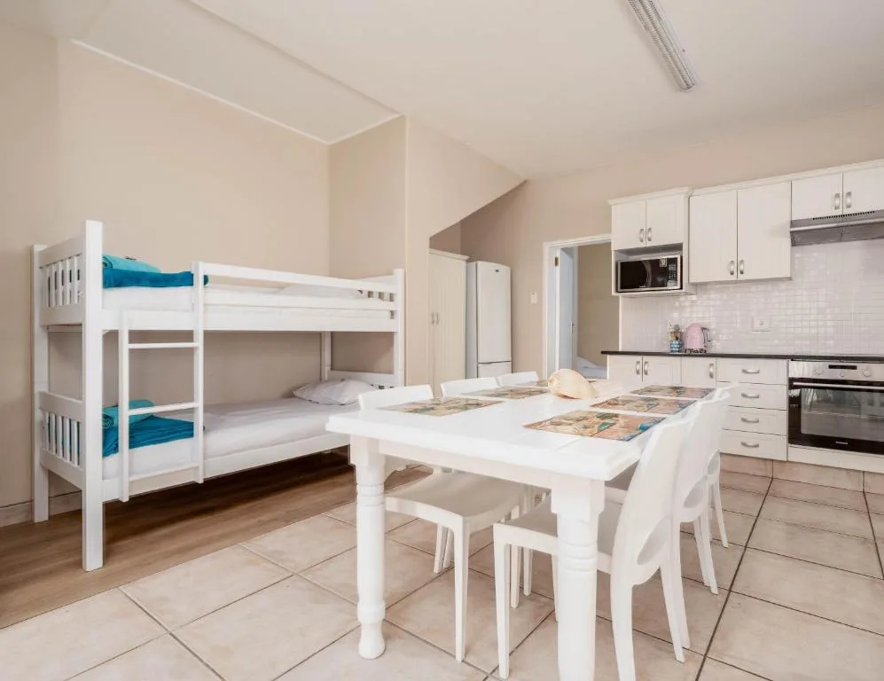 Open-plan bedroom with white bunk beds and integrated kitchen area