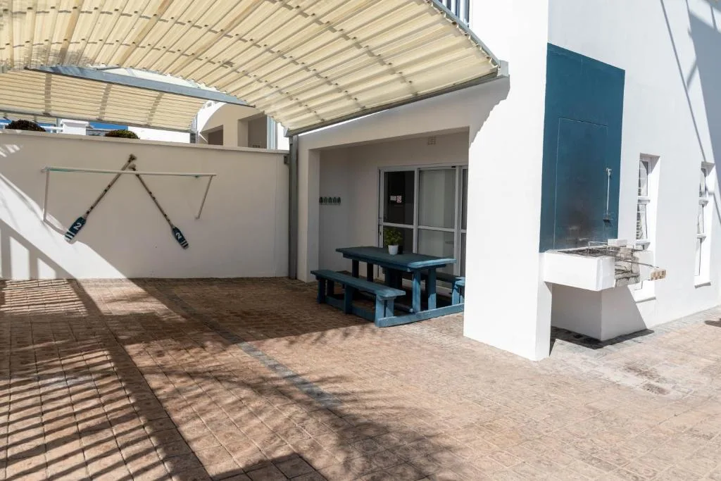 Shaded patio area with blue picnic table and pergola overhead