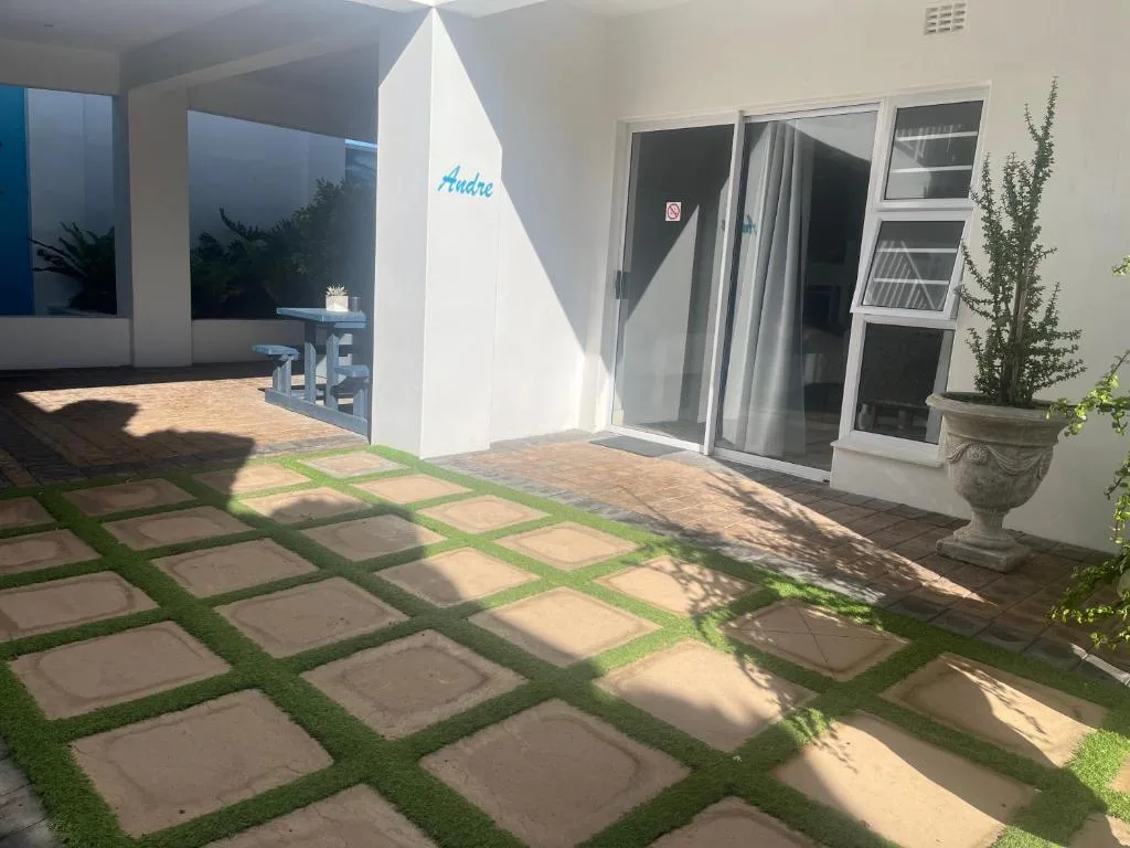Patio courtyard with geometric paving, grass strips, and potted plants