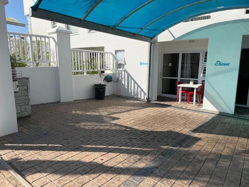 Covered patio with blue shade cloth, red seating, and white railings