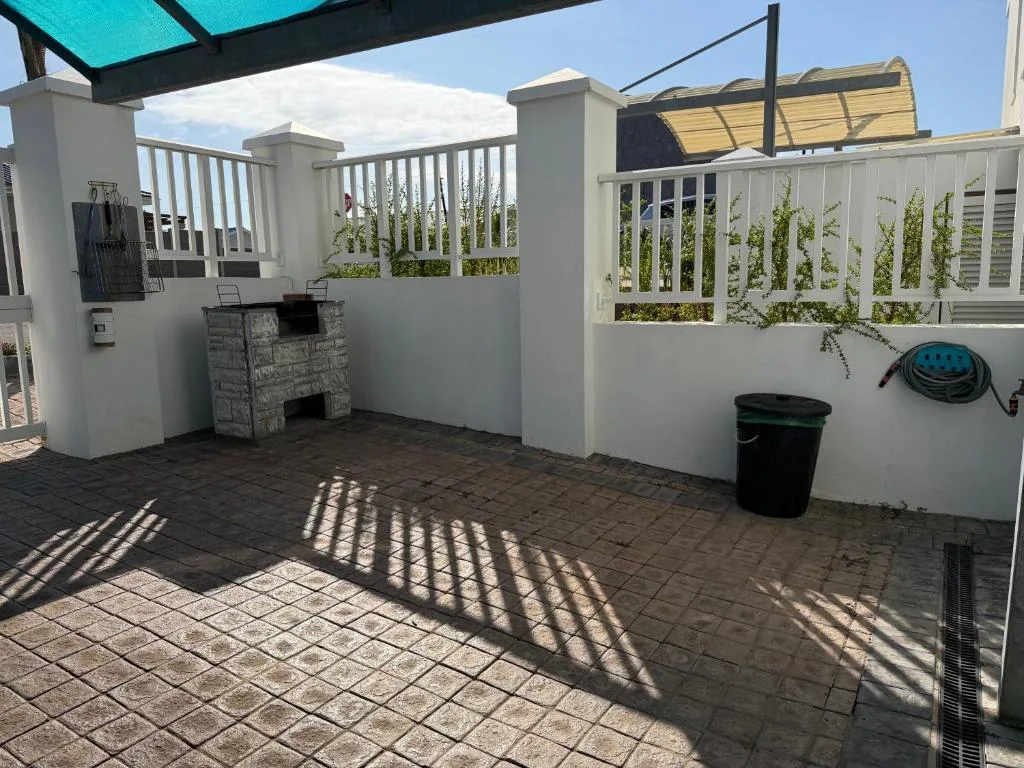 Covered outdoor patio with braai area and white railings