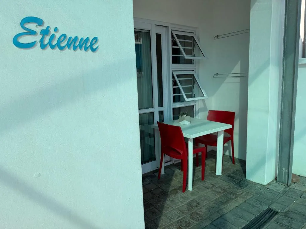 Small patio with white table and red chairs near property entrance