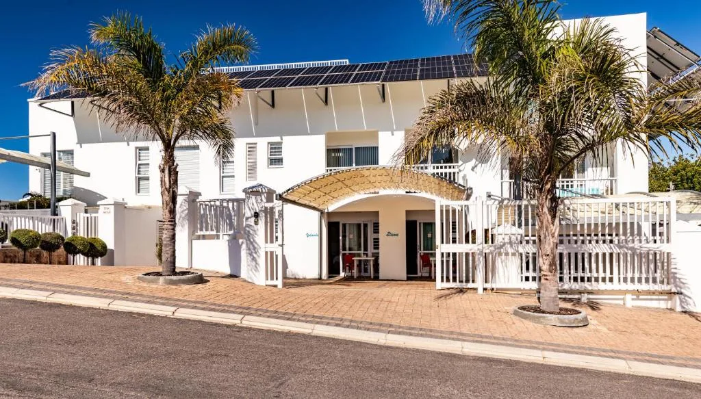 Modern white apartment building with palm trees and paved courtyard entrance