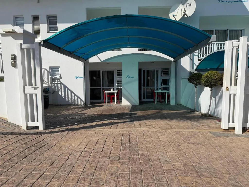 Modern white apartment building with blue curved awning and paved courtyard entrance