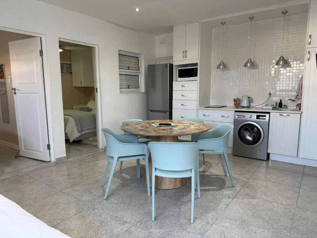 Modern open-plan kitchen with white cabinetry, dining table, and appliances