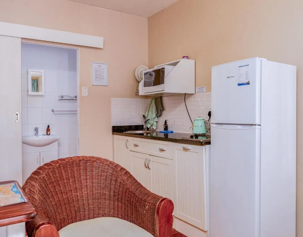 Compact kitchen with white cabinetry, black countertop, and white refrigerator