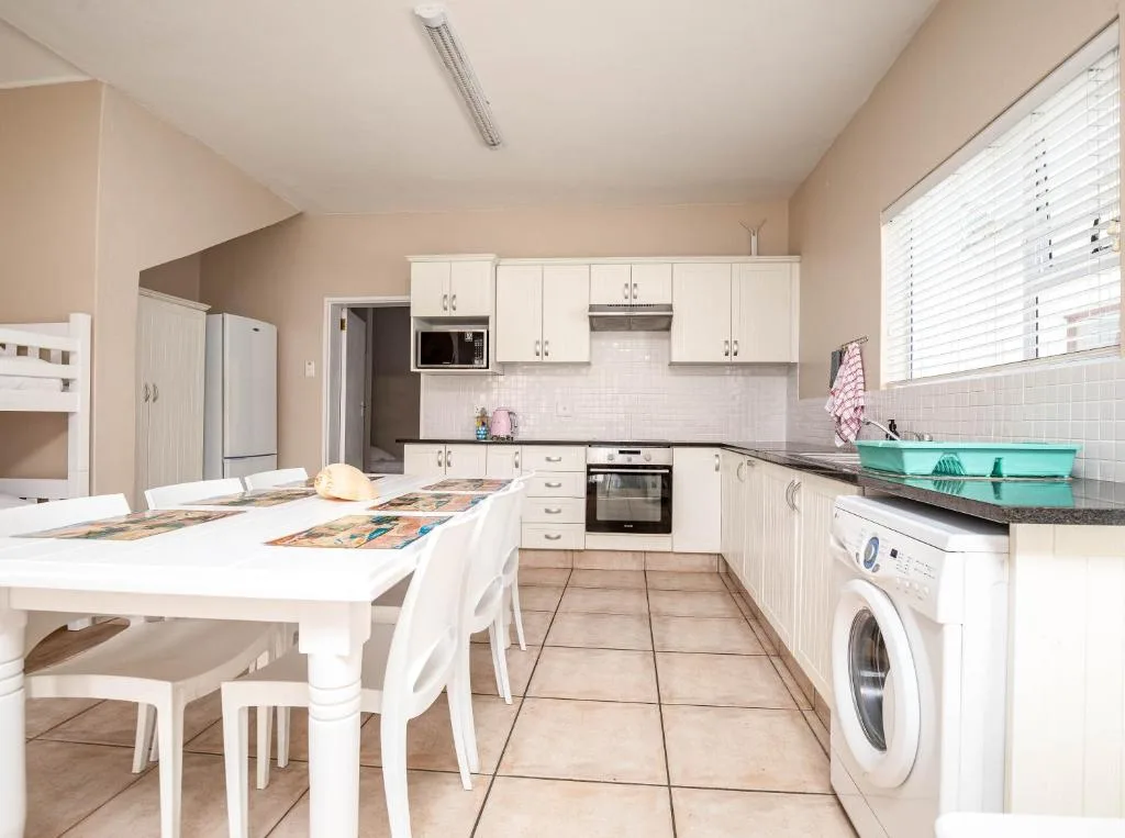 Spacious modern kitchen with white cabinetry, dining table, and appliances