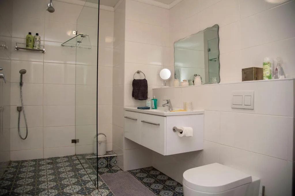 Modern bathroom with walk-in shower, white vanity, and patterned floor tiles
