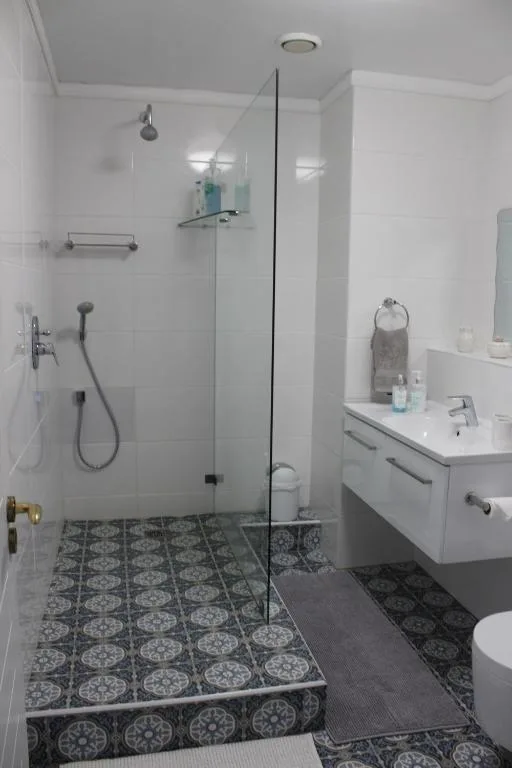 Modern bathroom with walk-in shower, vanity sink, and patterned tile flooring