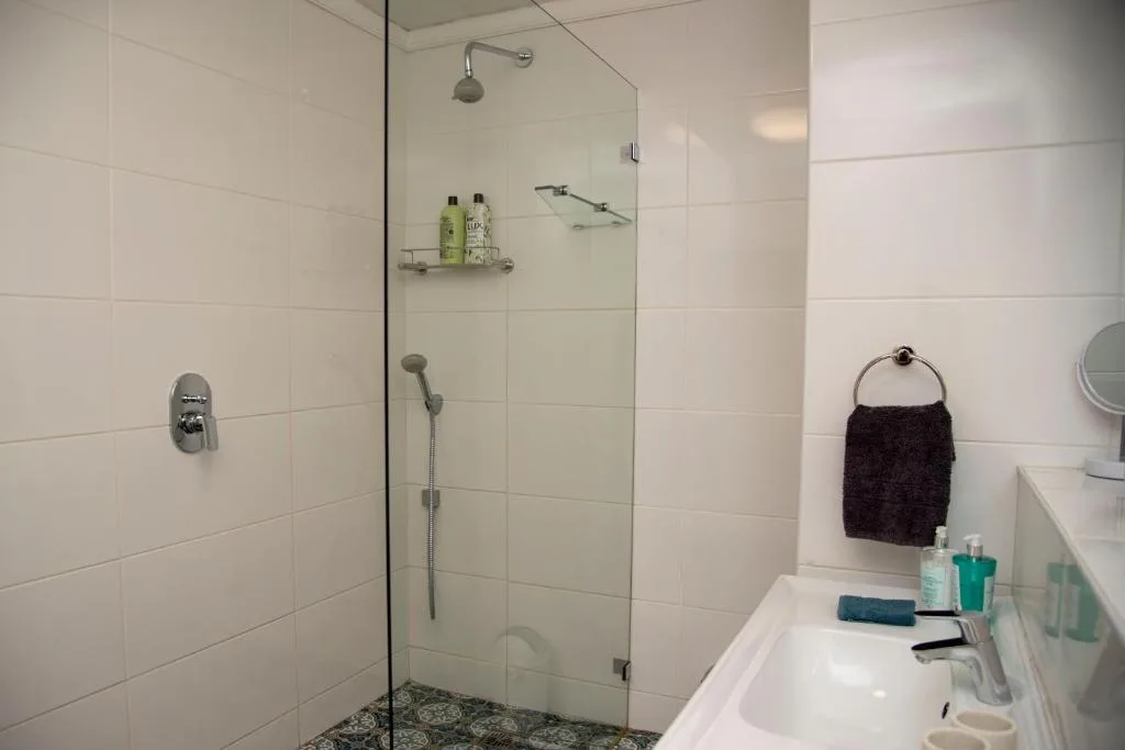 Modern shower enclosure with rain showerhead and white subway tile walls