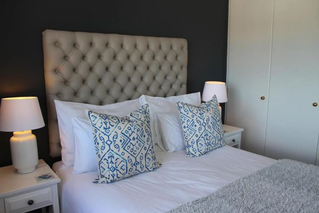 Contemporary bedroom with tufted headboard and blue patterned cushions