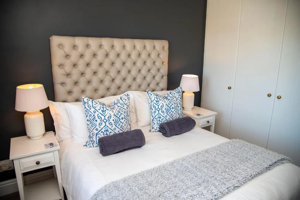 Modern bedroom with tufted headboard, white linens, and blue patterned pillows