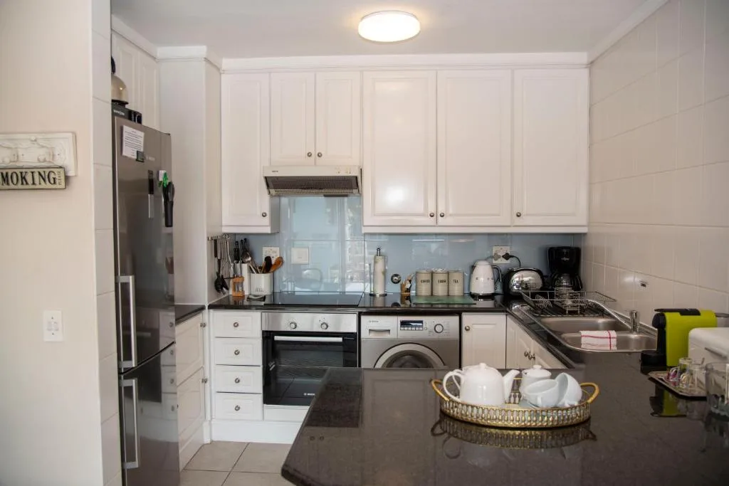 Modern white kitchen with stainless appliances and dark countertops