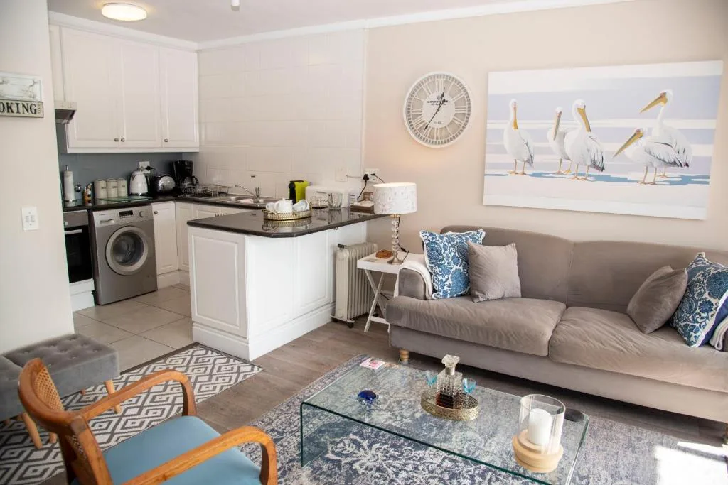 Open-plan living area with gray sofa, kitchen island, and coastal artwork