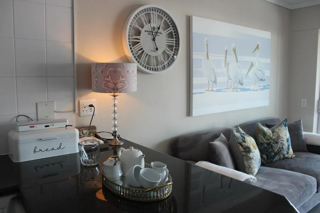 Modern lounge with gray sofa, decorative pillows, and coastal artwork on wall