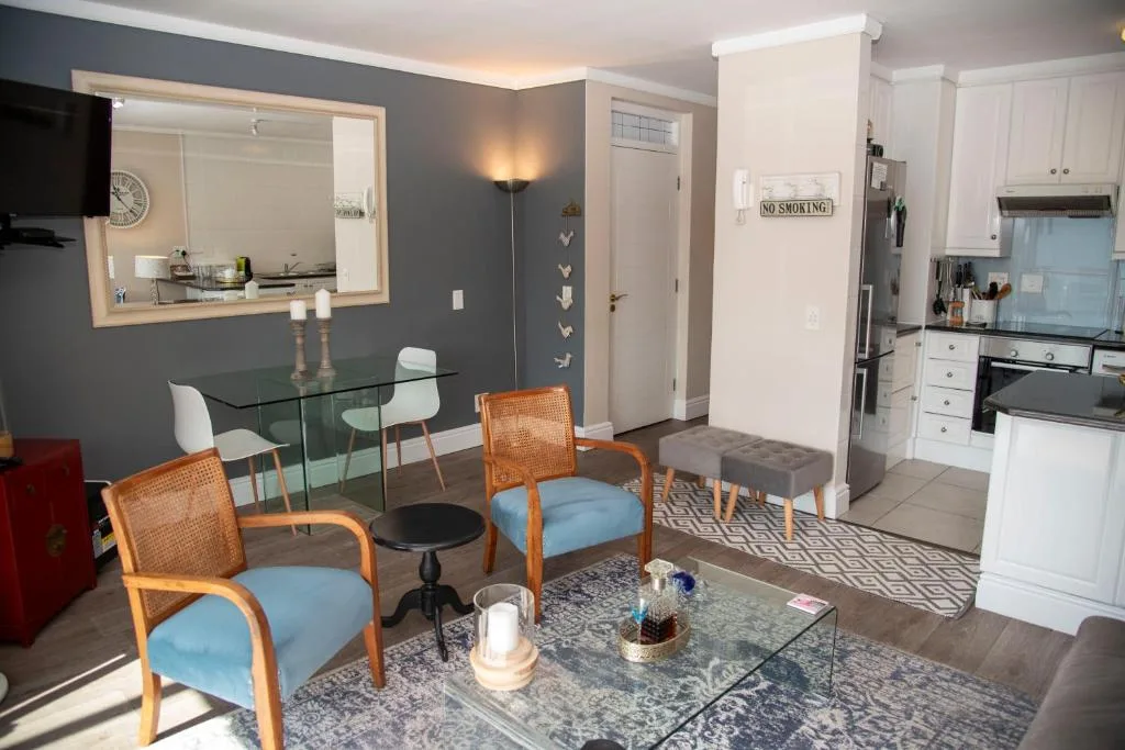 Open-plan lounge with blue accent chairs and glass dining table nearby
