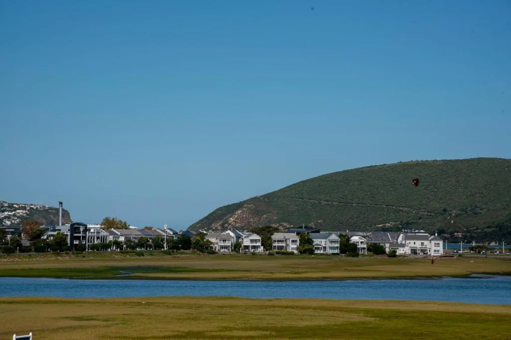 Waterfront homes with lagoon and green hills beyond under clear blue sky
