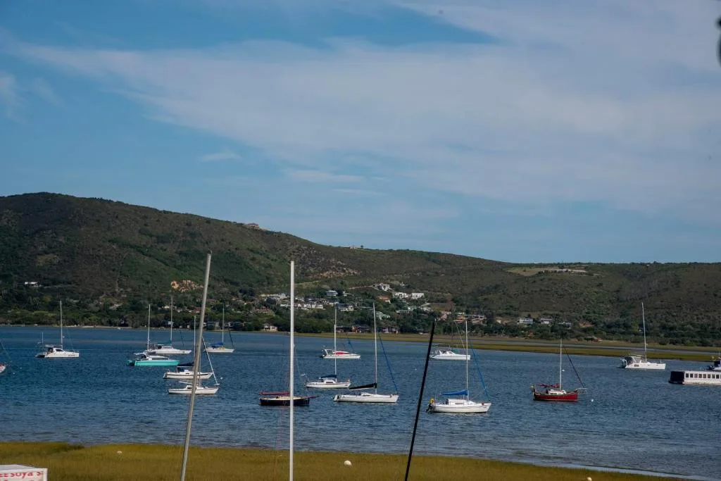Scenic waterfront view of Knysna lagoon with moored sailboats and green hills