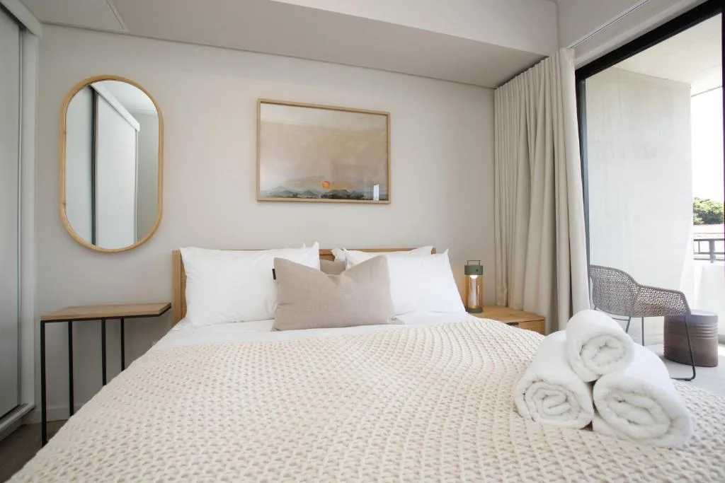 Spacious modern bedroom with queen bed, white linens, and deck access