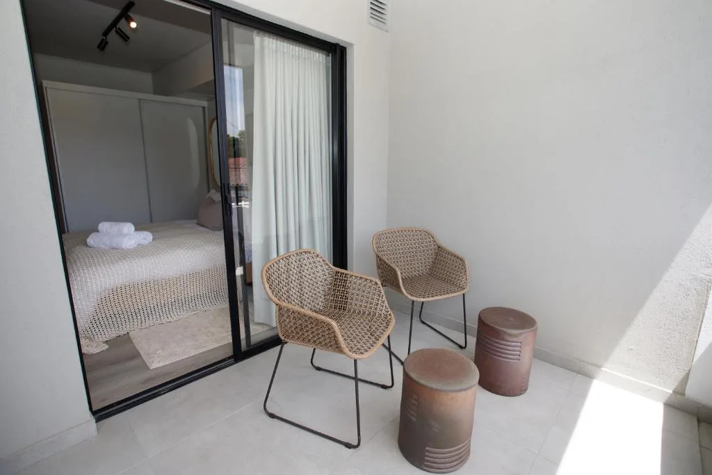 Outdoor seating area with woven chairs and ceramic stools overlooking bedroom