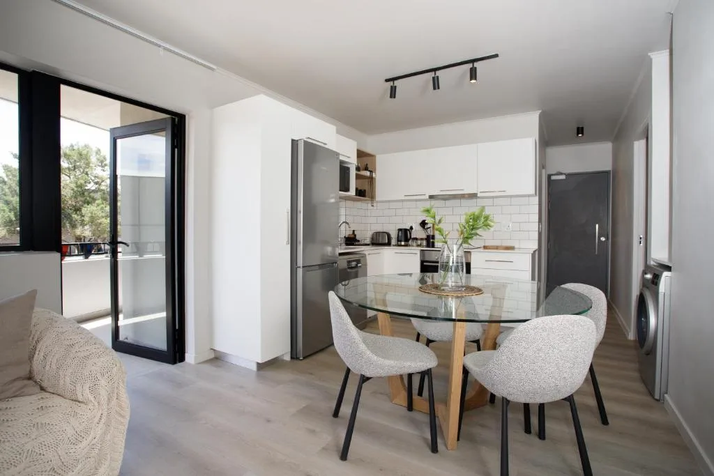Modern dining area with round black table and cream chairs in open-plan kitchen